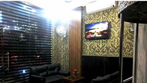 Una habitación con un sofá de cuero negro, una pequeña mesa de centro de madera y un televisor instalado en una pared con diseño.