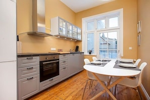 A modern kitchen with grey cabinets, a built-in oven, and a dining area with a white table and chairs. - Beautiful apartment in heart of RVK (Reykjavík)