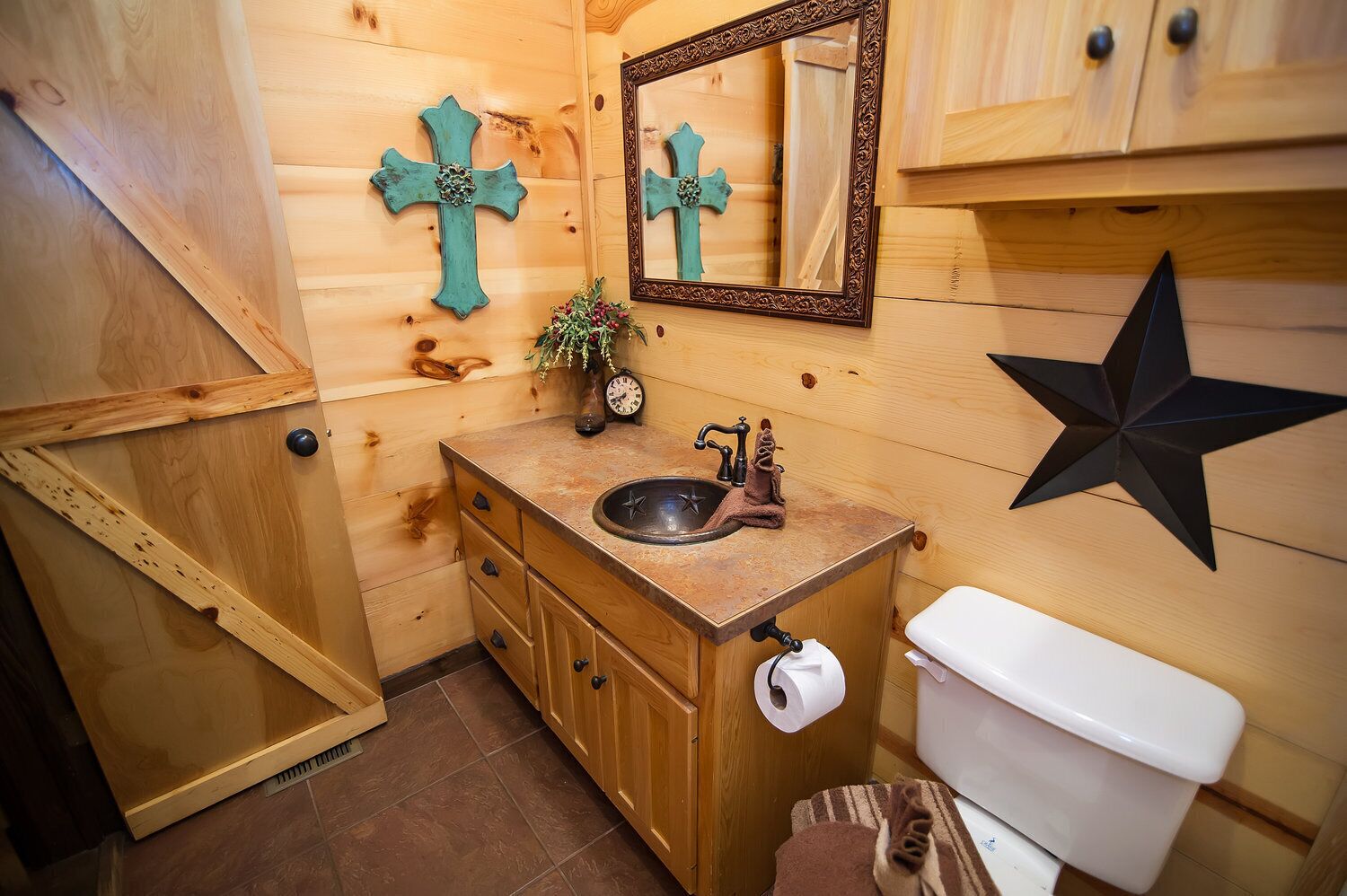 A wooden bathroom with a sink, toilet, and decorative crosses.
