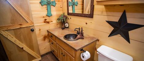A wooden bathroom with a sink, toilet, and decorative crosses.