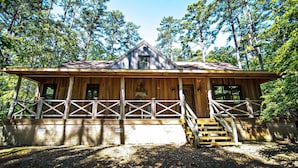 A wooden cabin with a porch and stairs, surrounded by trees. - Crazy Horse is a charming Hochatown Cabin with all the Amenities. (Broken Bow)