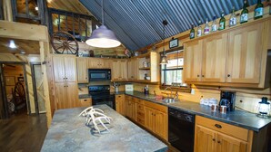 A kitchen with wooden cabinets, a microwave, a sink, and a large island. - Crazy Horse is a charming Hochatown Cabin with all the Amenities. (Broken Bow)
