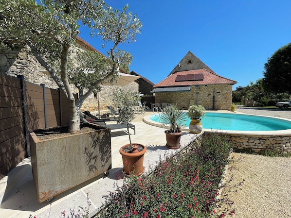 A stone building with a red-tiled roof, a swimming pool, and outdoor seating. - Beautiful totally restored holiday house with private pool (Rampoux)