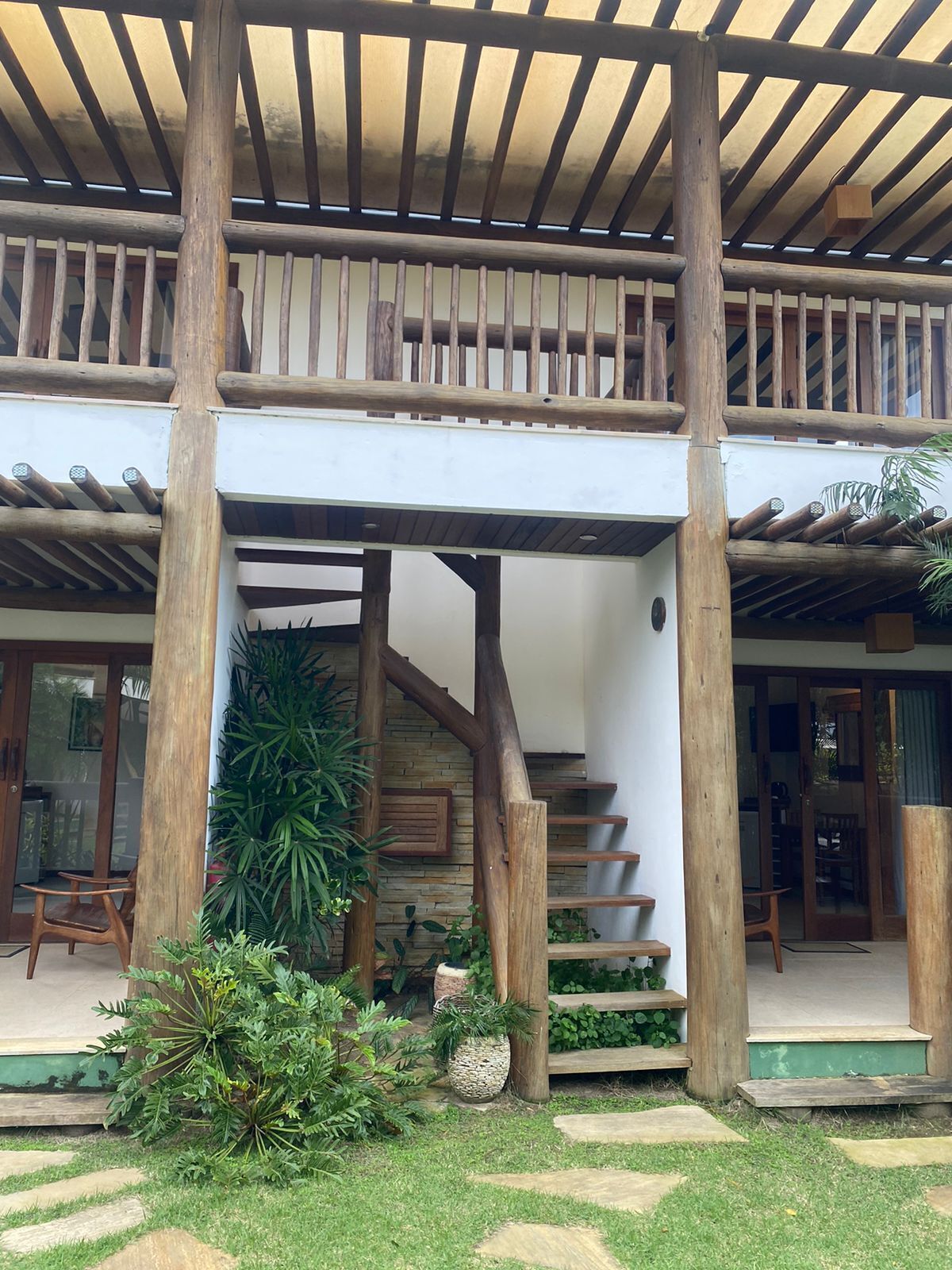 A wooden staircase leading to a covered outdoor area with a pergola overhead.