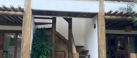 A wooden staircase leading to a covered outdoor area with a pergola overhead.