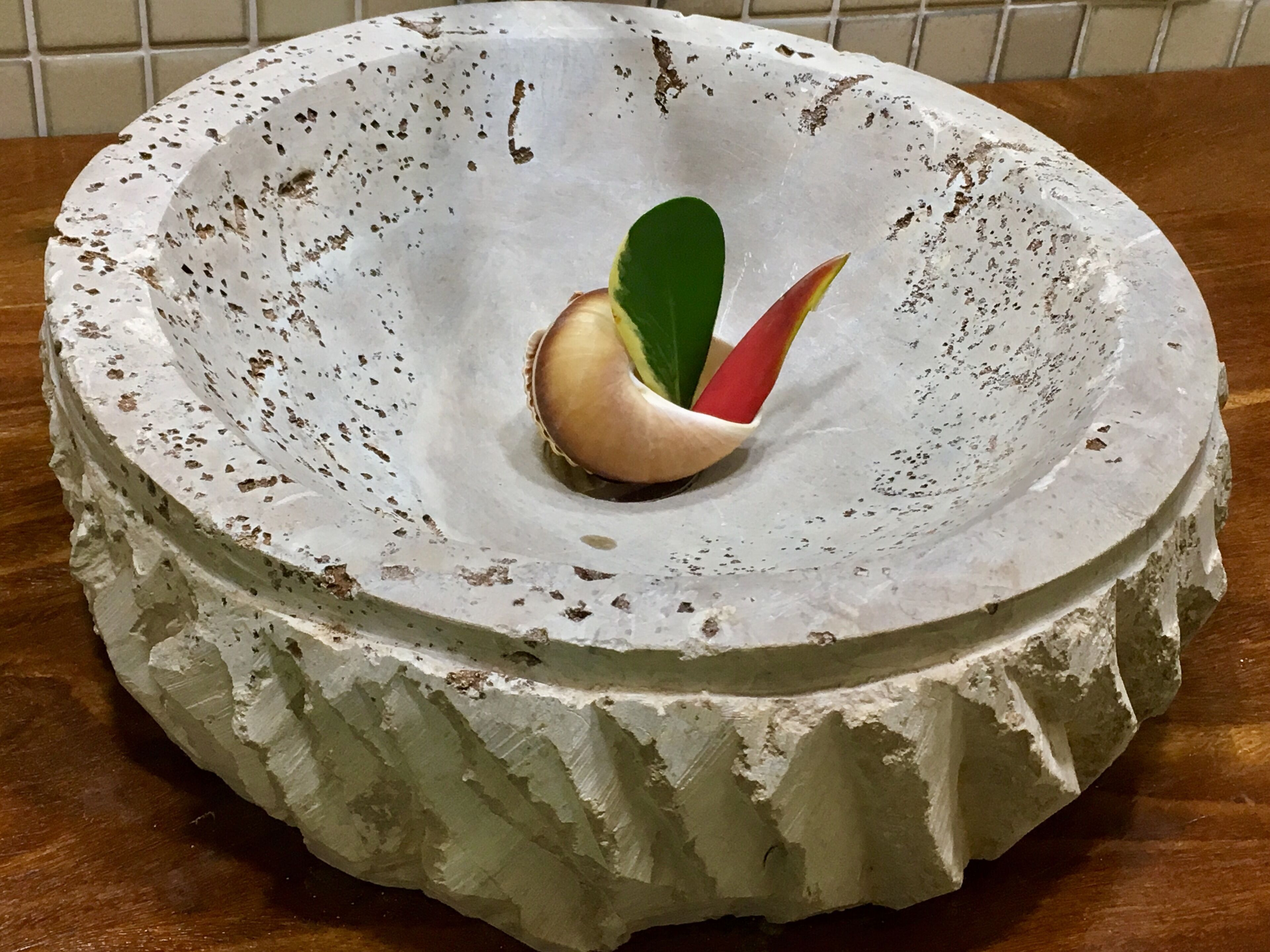 A cake with a green leaf and a red and yellow flower on top, placed on a white, speckled plate.