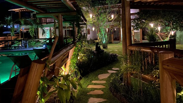 A nighttime outdoor area with a wooden pergola, a pool, and a garden path. - Carapitangui Pousada (Maraú)