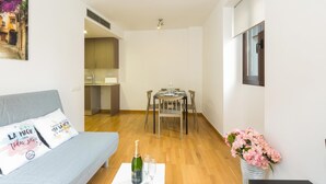 Un espacio habitable compacto con un sofá, una mesa de comedor y una pequeña cocina.