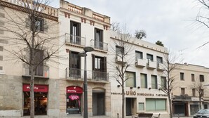 Vista de una calle con edificios, un banco y un coche.