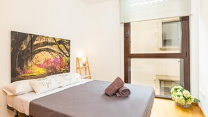 Un dormitorio con cama, un cuadro, una lámpara y una ventana.