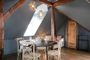 A dining area with a round table, chairs, and pendant lights.