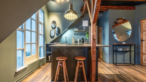 Una cocina con barra, taburetes de madera y un ventanal amplio.