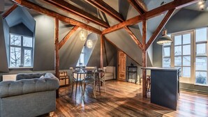 Una habitación tipo loft con vigas de madera a la vista, un comedor y una zona de estar acogedora.
