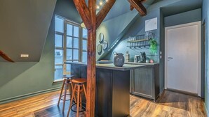 Una cocina con una isla central, taburetes de madera, un ventanal y una puerta.