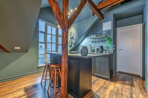 Una cocina con una isla central, taburetes de madera, un ventanal y una puerta.
