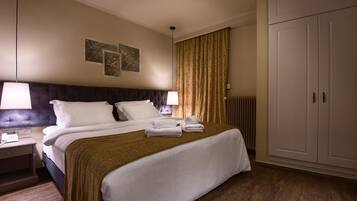 Une chambre d’hôtel avec un grand lit, deux lampes de chevet, une table de chevet, un radiateur et une armoire.