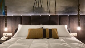 A neatly made bed with white bedding and a brown striped pillow, a bedside telephone, and a wall-mounted light fixture. - Hotel Kentrikon (Gortynia)