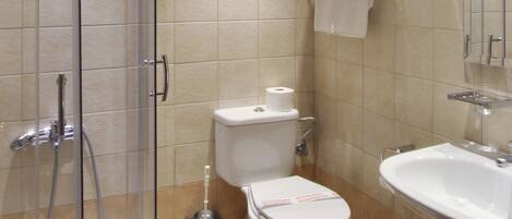 A bathroom with a glass-enclosed shower, a toilet, and a sink.