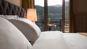 A hotel room with a large bed, a bedside lamp, and a balcony with a table and chairs. - Hotel Kentrikon (Gortynia)