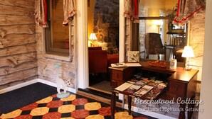 Een knus blokhut interieur met een stenen open haard, een houten bureau met boeken en een decoratie in de vorm van een kat.
