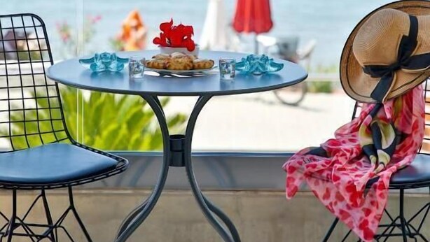 Un balcón con una mesa dispuesta para dos, con vista al mar.