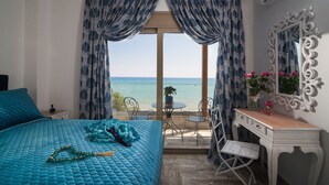 Un dormitorio con cama, escritorio, silla, mesa y vista al mar.