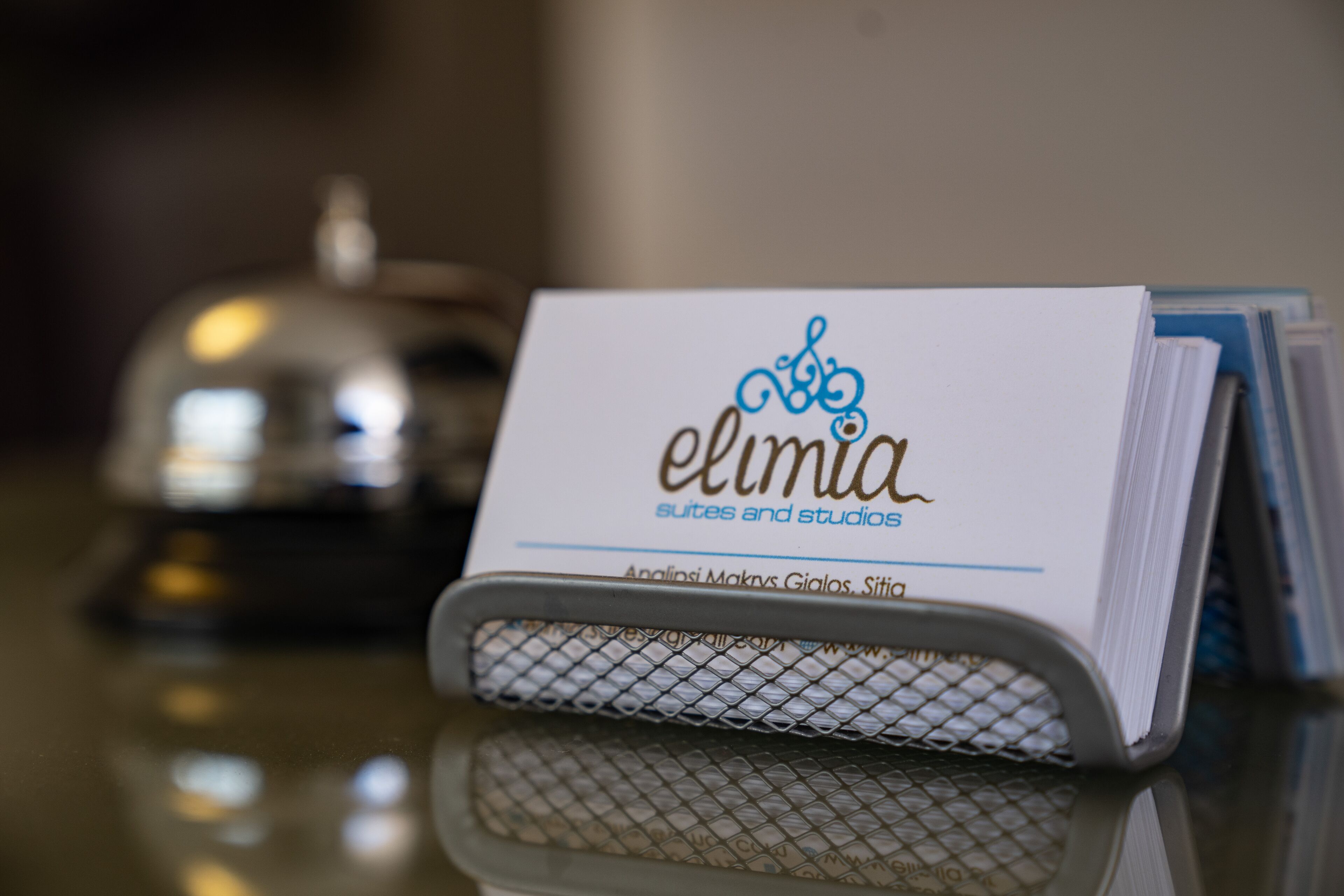 A business card for 'Elimia Suites and Studios' with a decorative logo and the text 'Analisi Makry Gialos, Sito'.