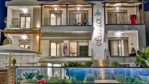 Un hotel de varios pisos con un atrio central, balcones y una fuente de agua al frente.