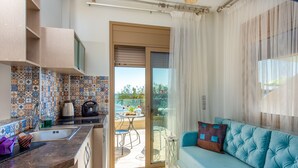 Una cocina moderna con salpicadero de azulejos, horno empotrado y un lavamanos. Hay una puerta corrediza de vidrio que da a un patio exterior con mesa y sillas. Un sofá azul está ubicado cerca de la puerta.