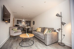 A modern living room with a grey sofa, a round coffee table, and a floor lamp.