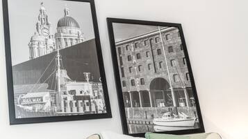 Two black and white framed photographs of buildings and a boat, mounted on a wall.