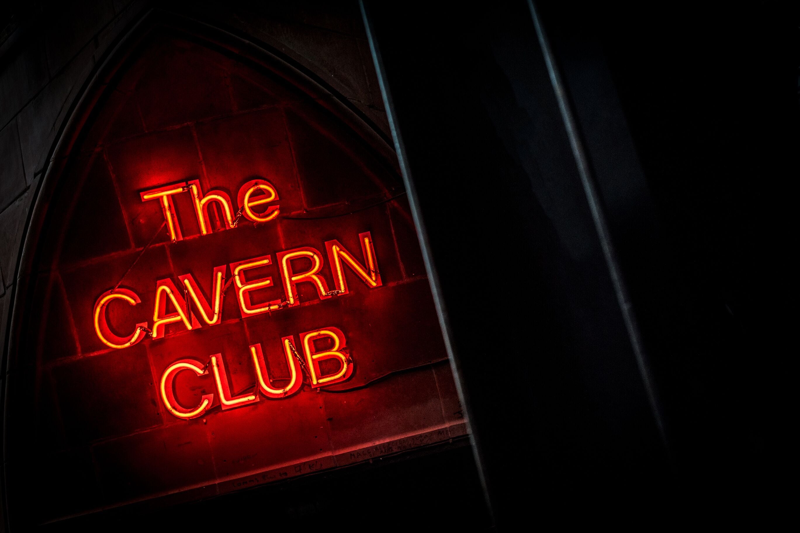 A neon sign reading "The Cavern Club" in a dark setting.