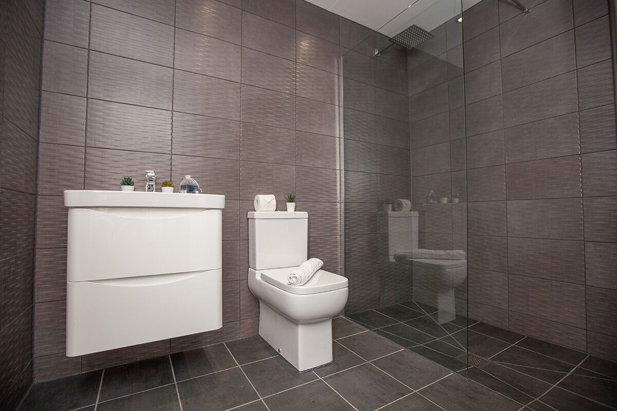 Une salle de bain moderne avec un meuble-lavabo blanc, des toilettes et un espace douche.