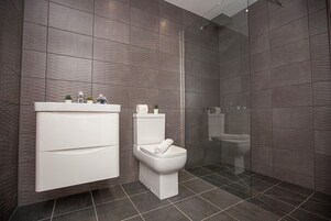 Un baño moderno con tocador blanco, inodoro y zona de ducha.