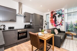 A modern kitchen with a built-in oven and a dining area with a wooden table and brown leather chairs.