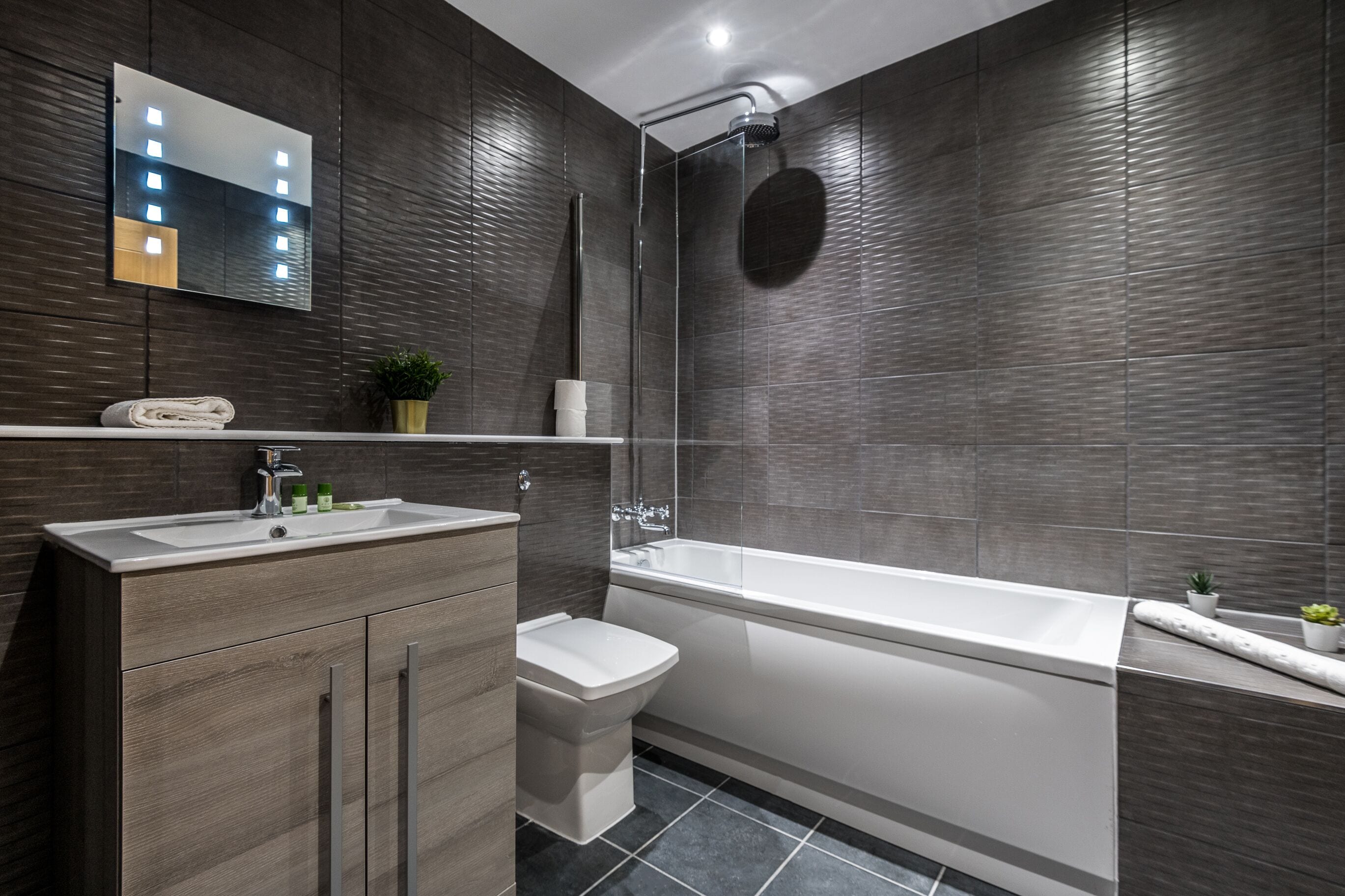 A modern bathroom with a large bathtub, a separate shower area, a vanity with a sink, and a toilet.