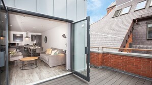 An open sliding door leading to a modern living space with a kitchen, a sofa, and a dining area. - SGT Pepper’s Apartments (Liverpool)