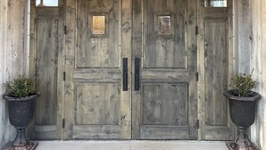A wooden double door with a logo above it, flanked by two potted plants. - Challis Roadhouse (Challis)