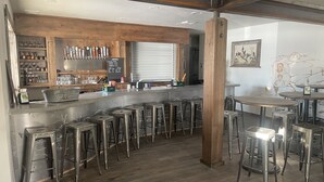 A bar area with stools, a bar counter, and a wooden ceiling. - Challis Roadhouse (Challis)