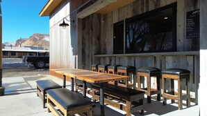 An outdoor seating area with wooden tables and benches, a blackboard menu, and a view of a mountain in the background. - Challis Roadhouse (Challis)