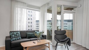 A modern living room with a black sofa, a wooden coffee table, and a black armchair. - SIF Apartments Central Reykjavik - 1 Bedroom (Reykjavík)