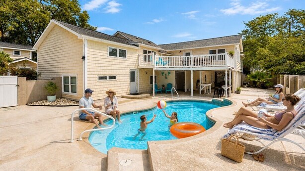 Ein Garten mit Swimmingpool, einer überdachten Terrasse und einem zweistöckigen Haus.