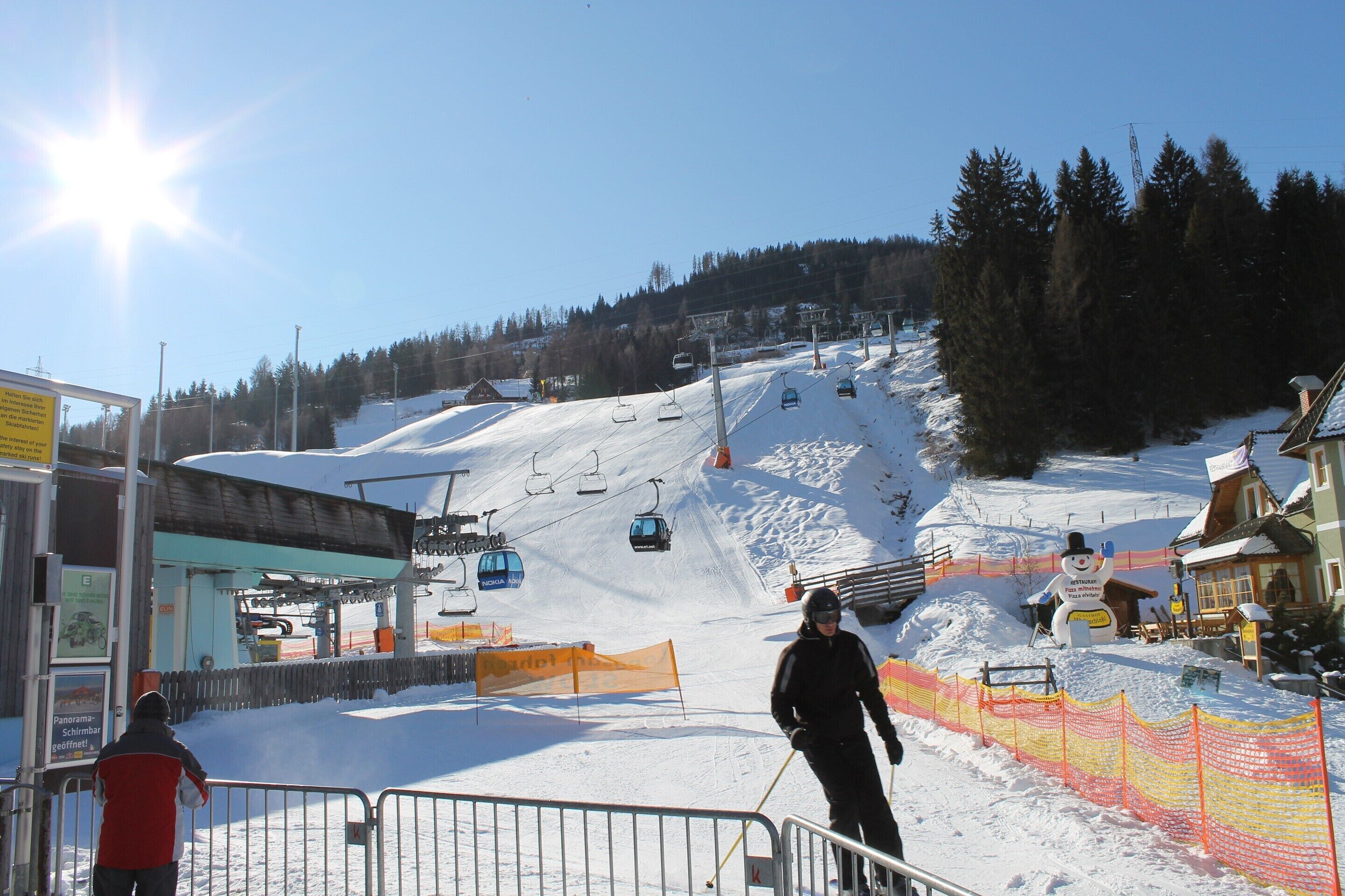 A ski resort with a chairlift, snow-covered slopes, and a wooden cabin.