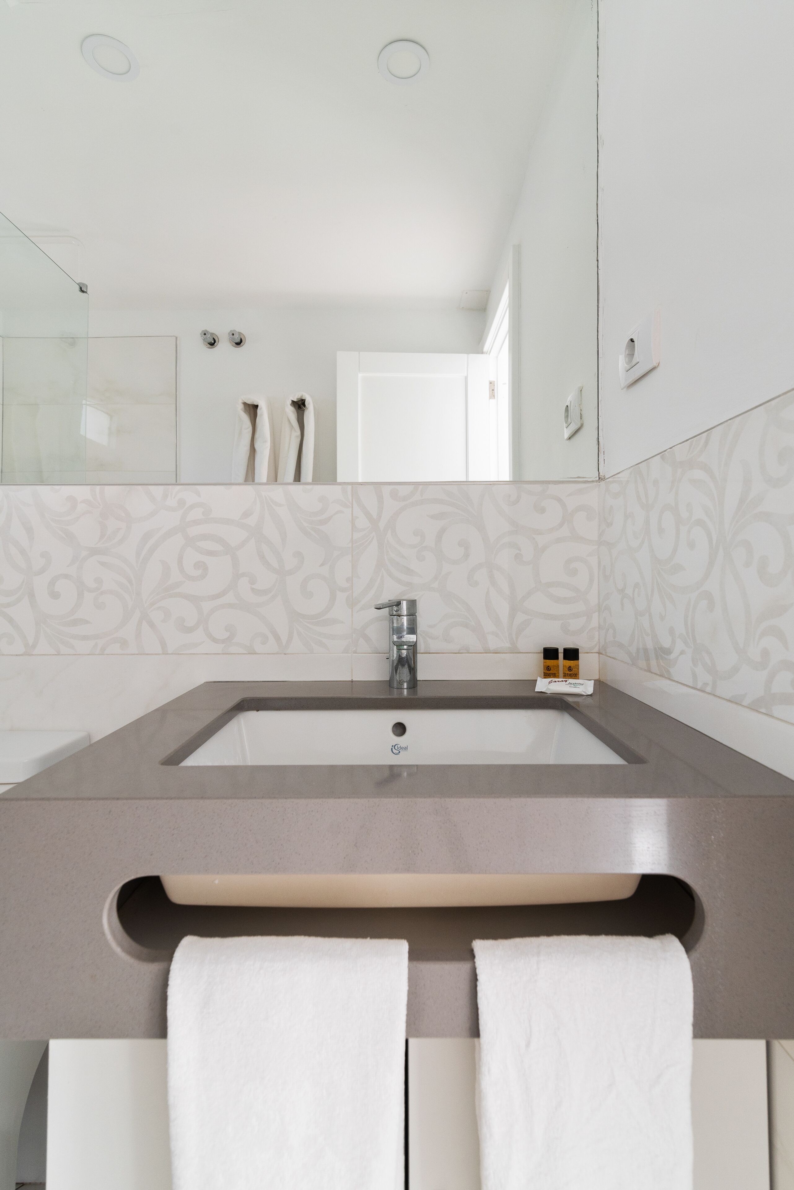 Un baño moderno con un lavamanos grande, un espejo y un perchero para toallas.