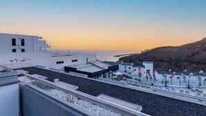 A rooftop terrace with a view of the sea and a hilly landscape.