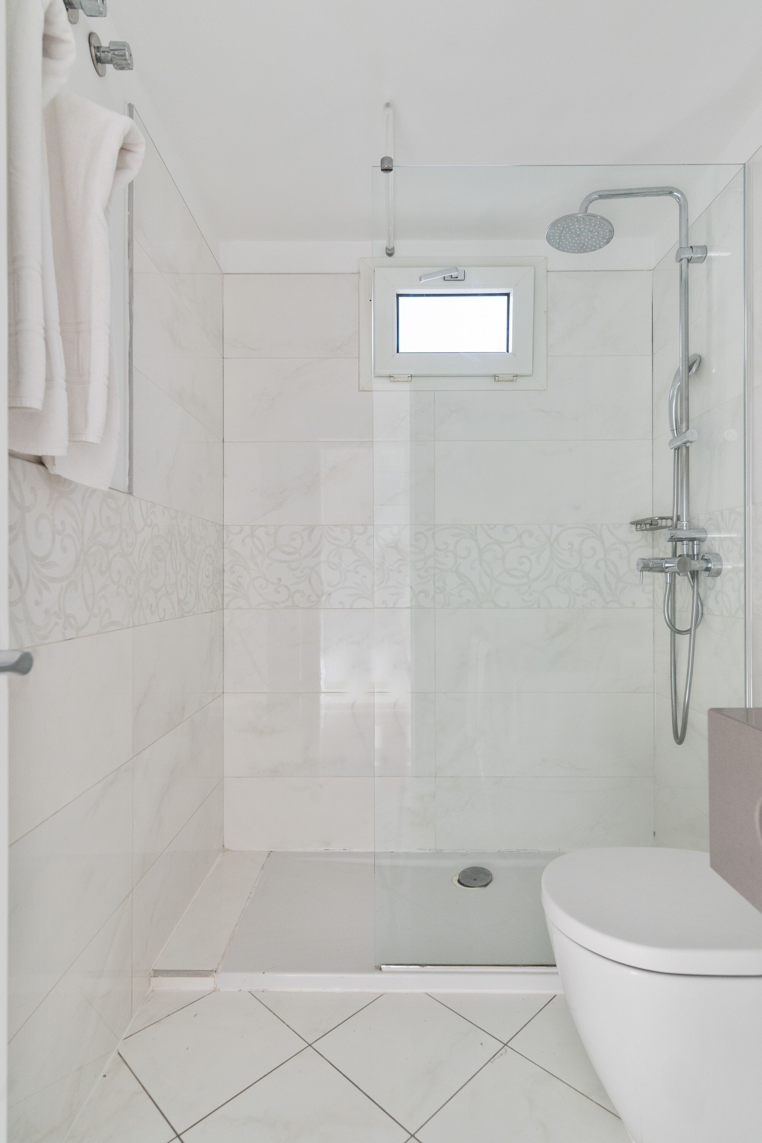 A modern bathroom with a glass-enclosed shower, a toilet, and a sink with a mirror.