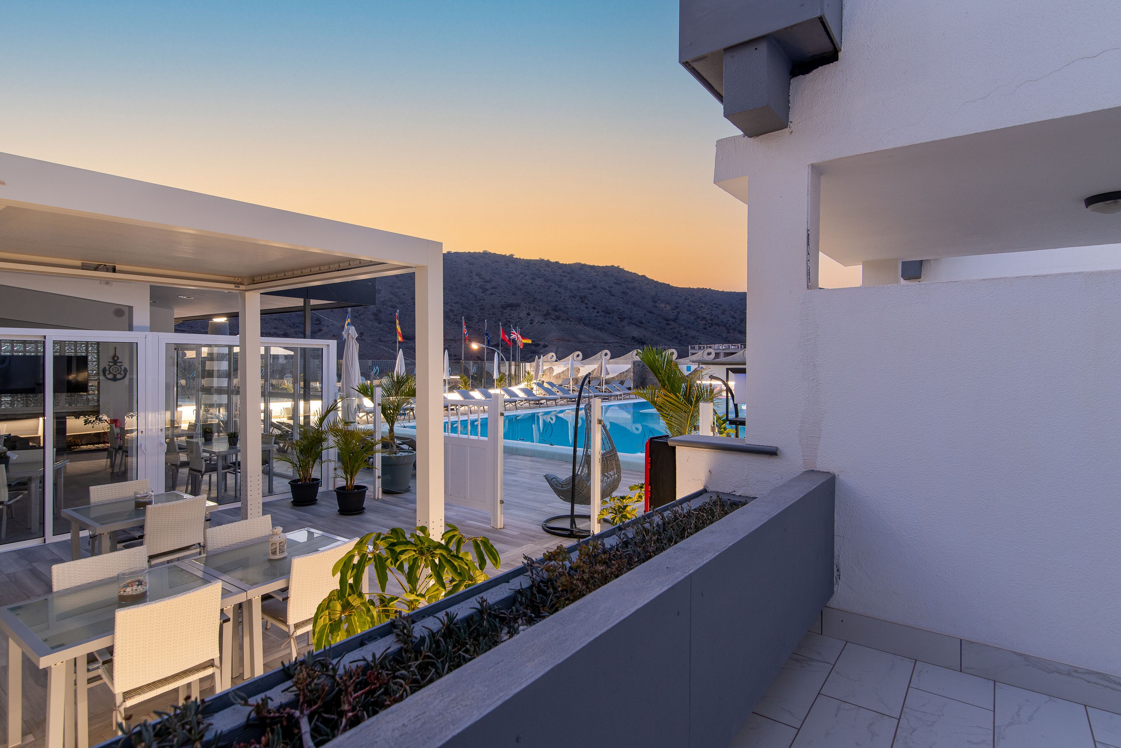 Una terraza moderna al aire libre con piscina, zona de estar y plantas en macetas.