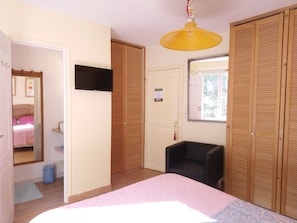 A bedroom with a bed, a television, wooden closets, a chair, and a window. - La Tonnelle (Vouvray)