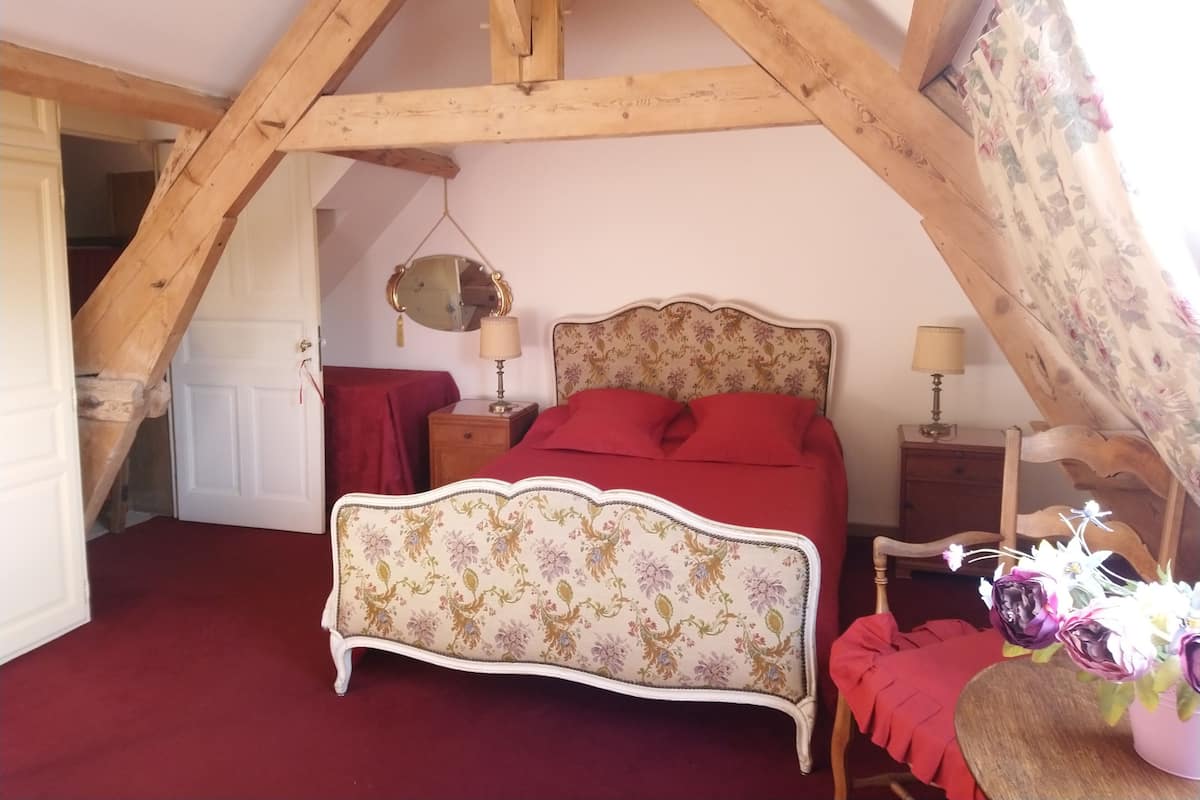 Un dormitorio con cama, dos mesitas de noche, un espejo y un cabecero estampado con motivos florales.