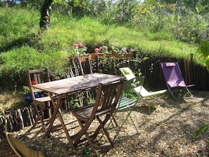 An outdoor patio area with a wooden table and chairs, surrounded by a wooden fence and lush greenery. - La Tonnelle (Vouvray)